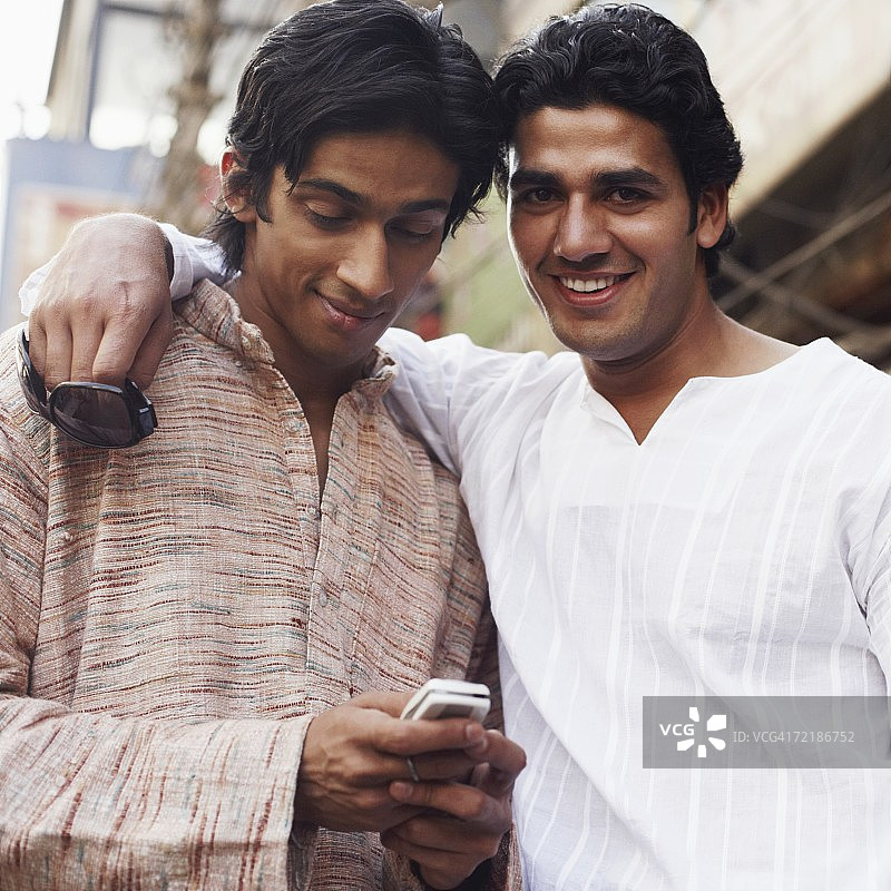 一个年轻人用手机和另一个人微笑的肖像图片素材