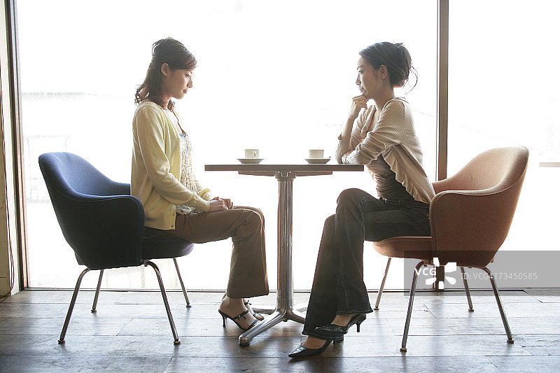 两名年轻女子坐在餐厅的侧影图片素材