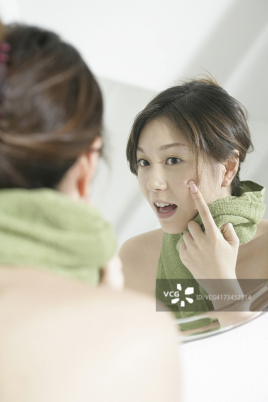 镜子里的一个年轻女人，手指放在脸颊上图片素材
