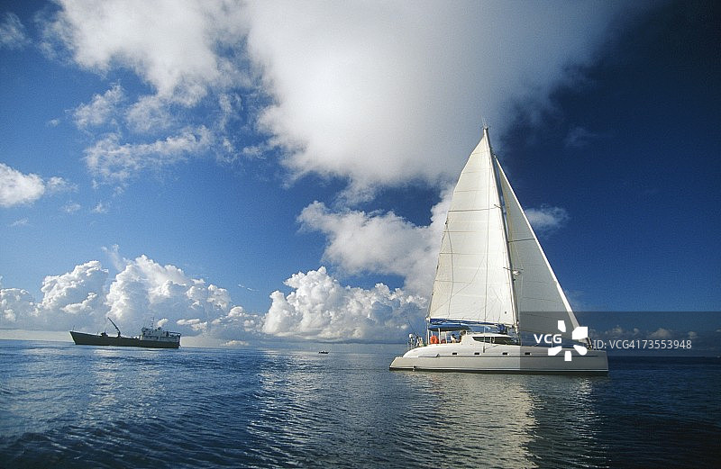 背景中的一艘帆船和一艘大型集装箱船的风景图片素材