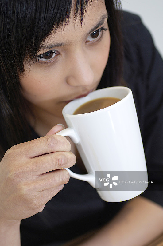 一幅年轻亚洲女性在喝咖啡休息的肖像图片素材