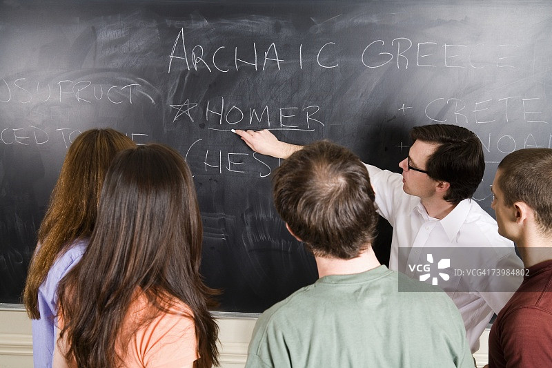 讲师在黑板上为一群学生写字图片素材