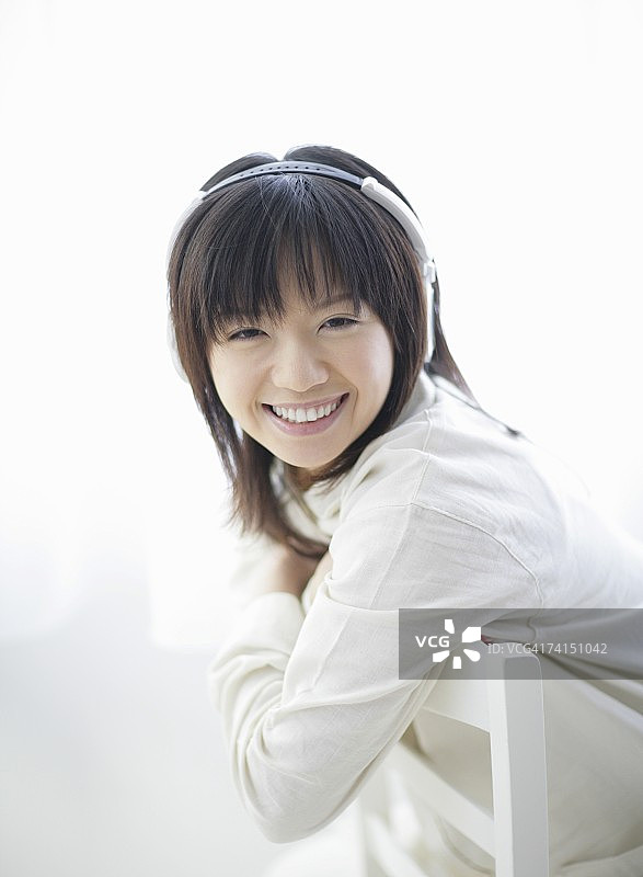 一个日本女人在房间里用耳机听音乐图片素材