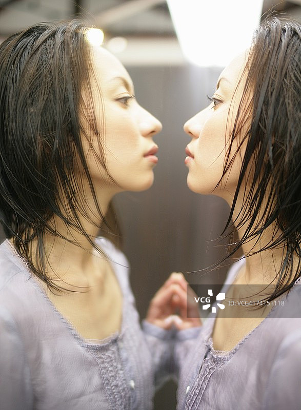 一个日本女人在镜子里看着自己的脸图片素材