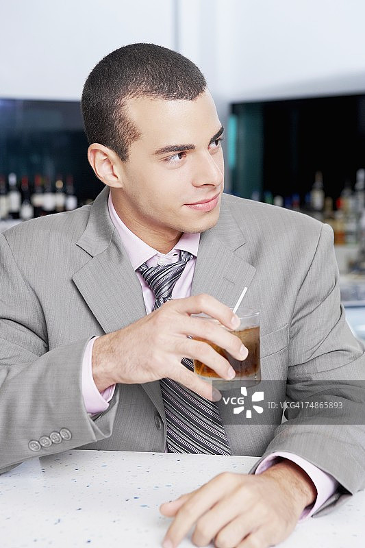 一个商人在酒吧里拿着一杯鸡尾酒的特写图片素材