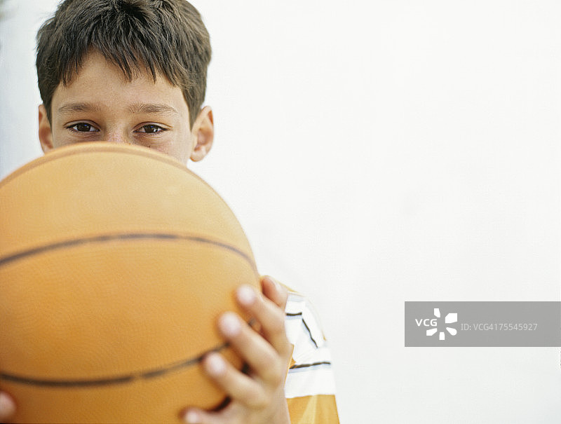 男孩(12-13岁)把篮球举过脸，肖像，特写图片素材