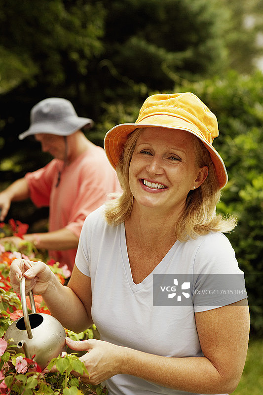 一个成熟女人的肖像，浇植物和微笑图片素材