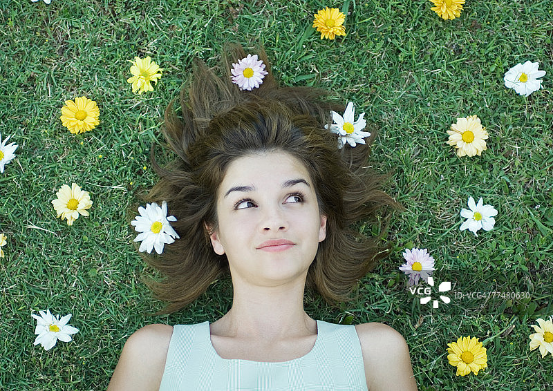 一个女人躺在草地上，头上撒满鲜花图片素材