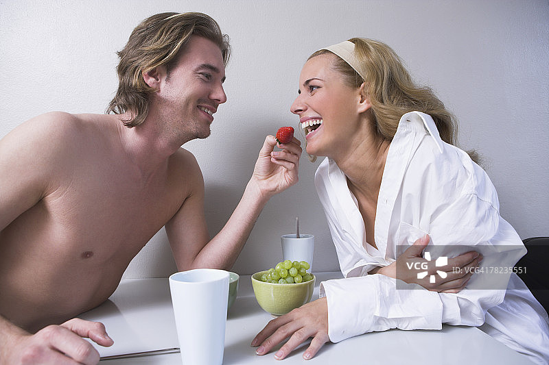 一对年轻夫妇坐在一起，男人给女人喂草莓图片素材