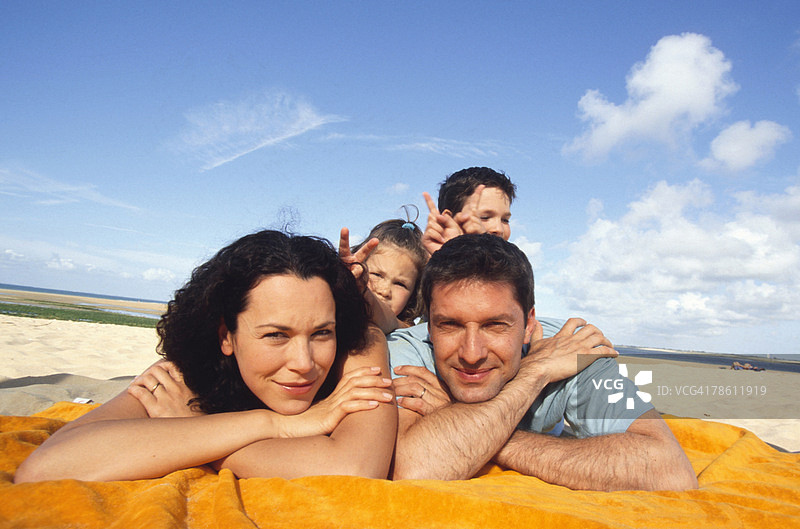 幸福的一家人躺在沙滩上图片素材