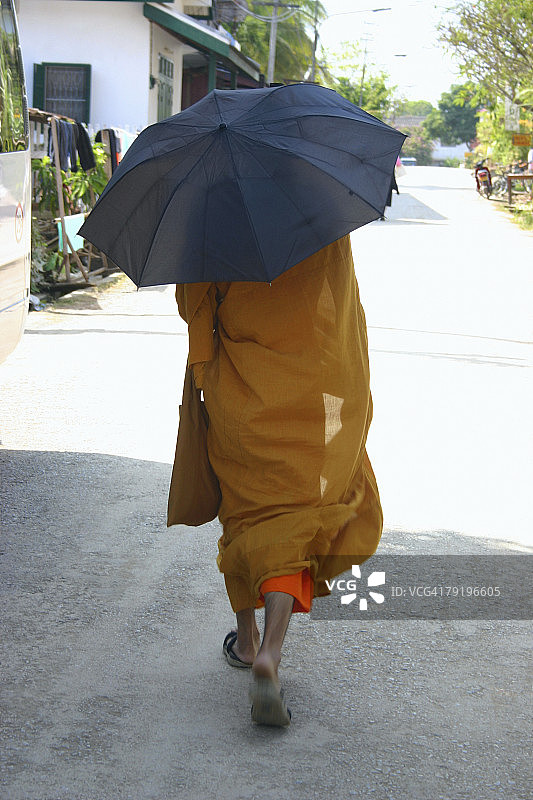 老挝万象，和尚撑着伞走在路上图片素材