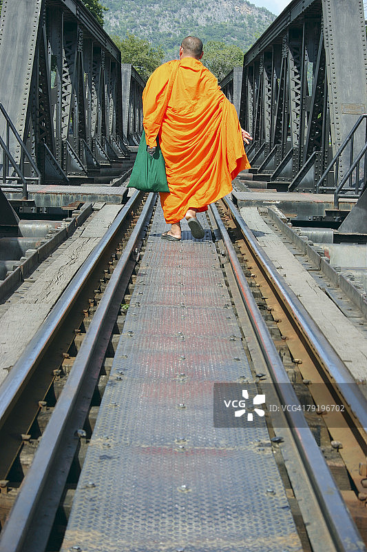泰国廊开，一个和尚走在铁路上的后视图图片素材