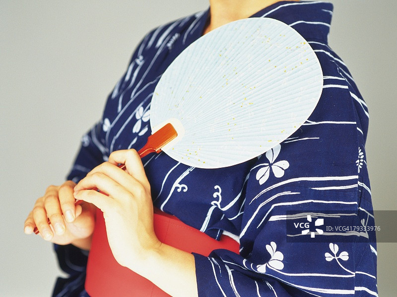 一个女人在浴田拿着日本扇子，侧视图图片素材