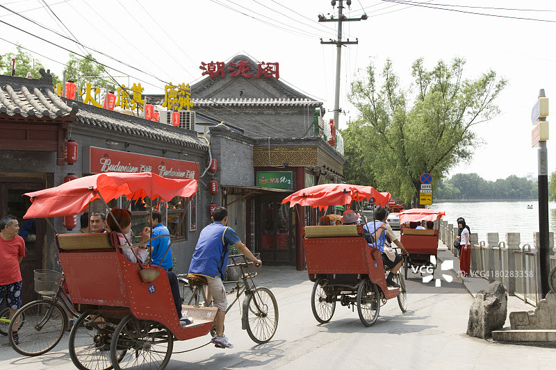 游客坐在中国人力车的后视图，中国，北京，胡同图片素材