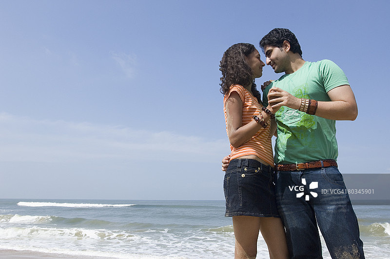 一个年轻男子在海滩上拥抱一个年轻女子的低角度视图图片素材