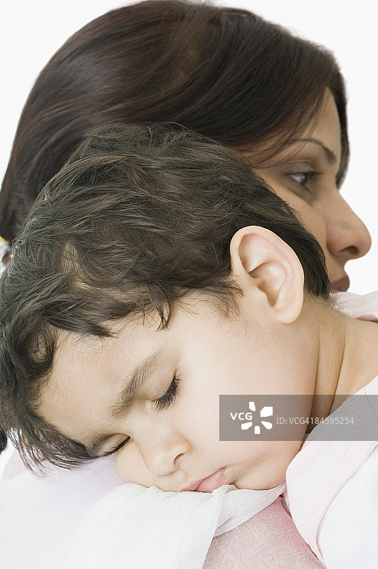 一个女孩在她妈妈的肩膀上睡觉的特写图片素材