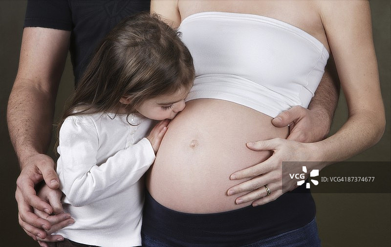 女孩亲吻怀孕的母亲图片素材