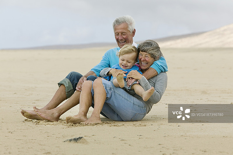 祖父母和蹒跚学步的孩子在海滩上玩图片素材