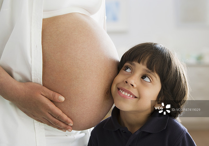 西班牙男孩在听motherÂ的怀孕的肚子图片素材
