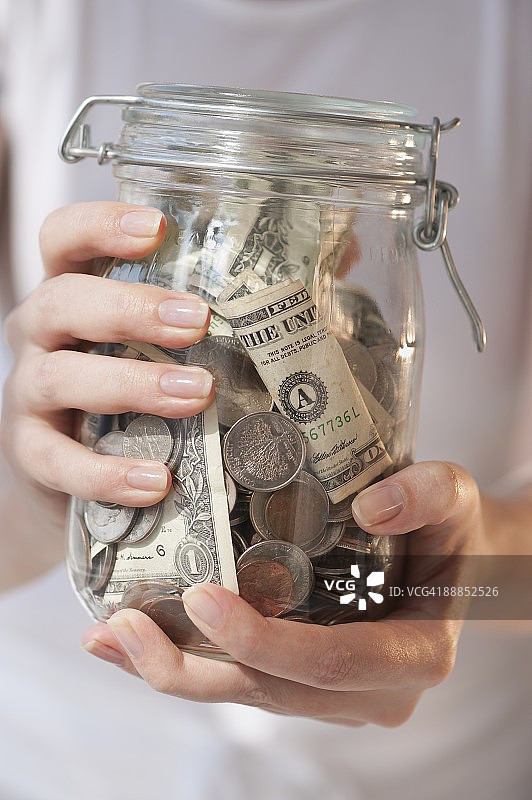 女人拿着一罐钱的特写图片素材