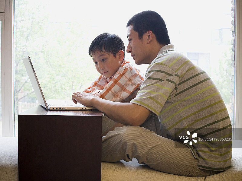父亲和儿子坐在电脑前图片素材