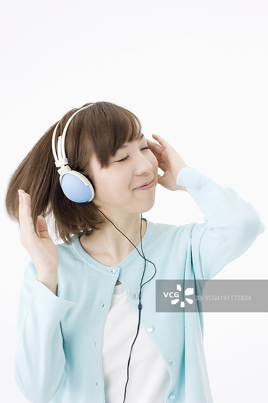 年轻女子戴着耳机听音乐，在录音棚拍摄图片素材