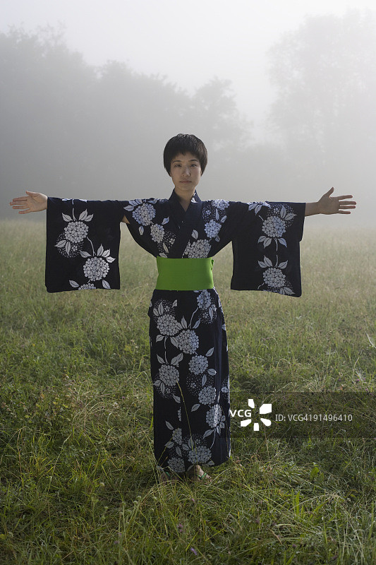 亚洲妇女穿着传统长袍站在野外图片素材