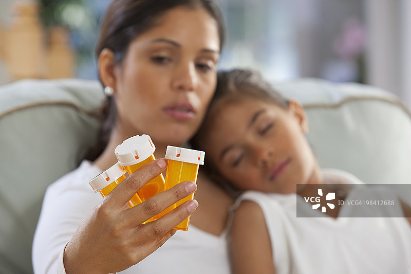 一位西班牙妇女拿着药瓶和女儿坐在一起图片素材