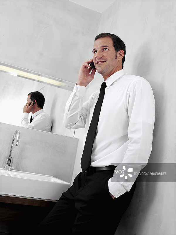 一幅年轻商人在浴室镜子前用手机聊天的肖像图片素材