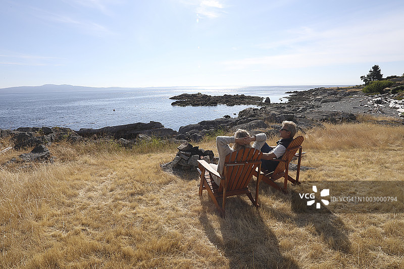 一对夫妇在木椅上休息，眺望着平静的大海图片素材