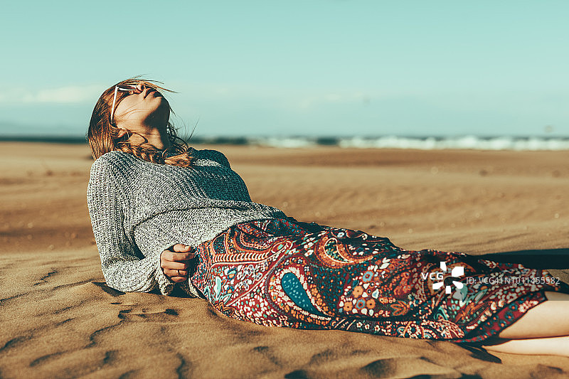 年轻女子躺在沙漠中图片素材