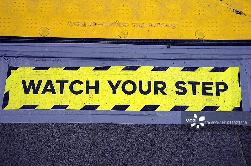 “小心脚下”的标志贴在城市街道人行道的塑料安全坡道旁图片素材