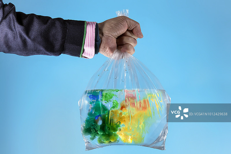 男人的手拿着一个装满水和丙烯酸颜料的塑料袋图片素材