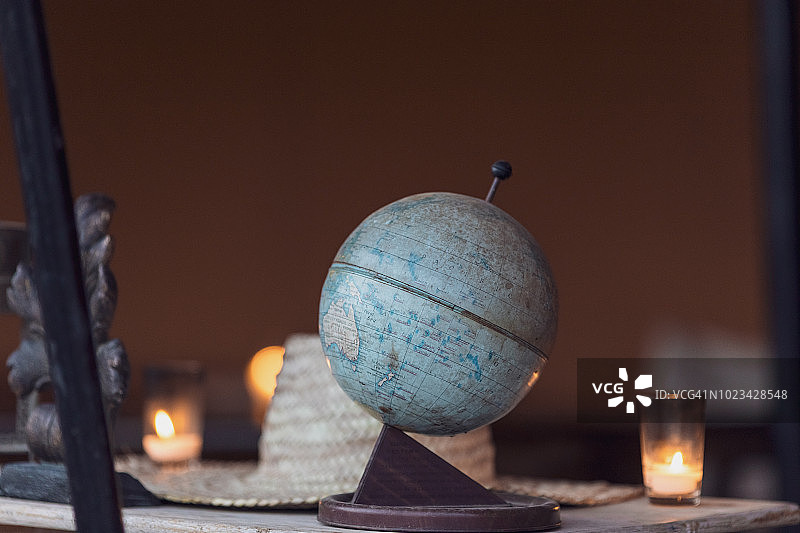 一个地球仪站在桌子上的特写，背景是一顶帽子和蜡烛。Marrakesh-Safi、摩洛哥马拉喀什。图片素材