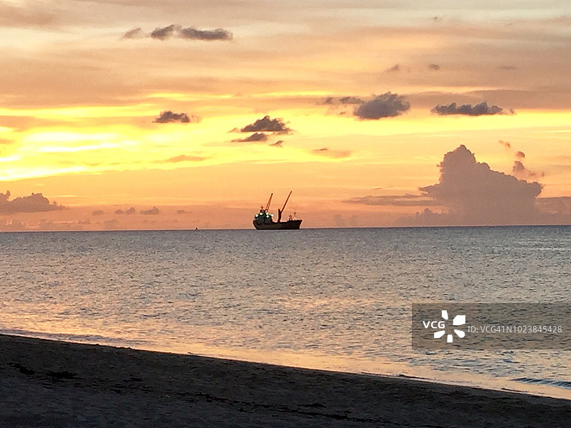 巴哈马群岛，天堂岛:日落后，在绚丽多彩的天空下，海上的一艘小船图片素材