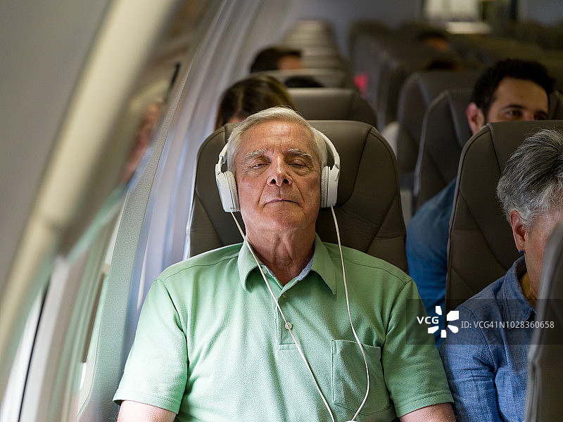 老人乘飞机旅行，边听音乐边睡觉图片素材