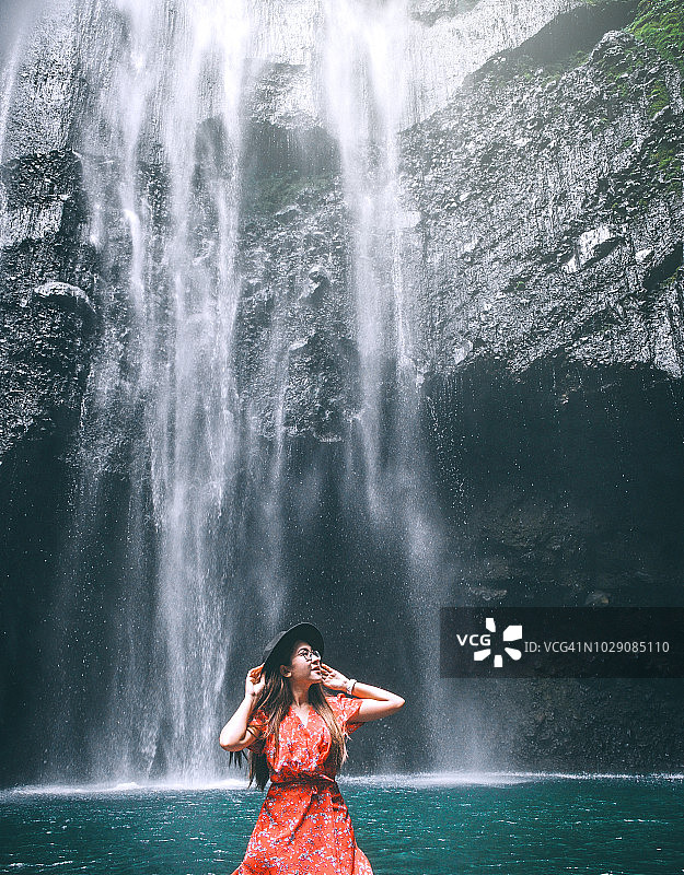 旅游女人冒险和站在Madakaripura瀑布放松，东爪哇岛，印度尼西亚图片素材