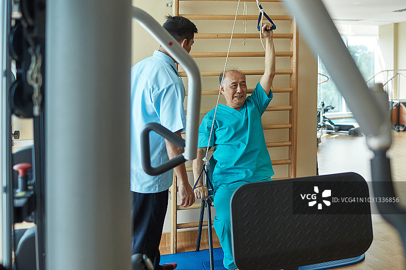 男护士看着病人在健身房锻炼图片素材