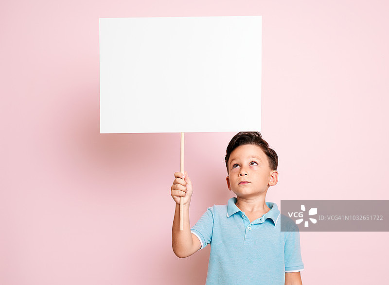 可爱的孩子拿着白色的海报。图片素材