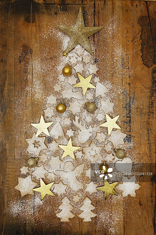 圣诞饼干，金色的圣诞装饰物和星星在木头上形成圣诞树图片素材