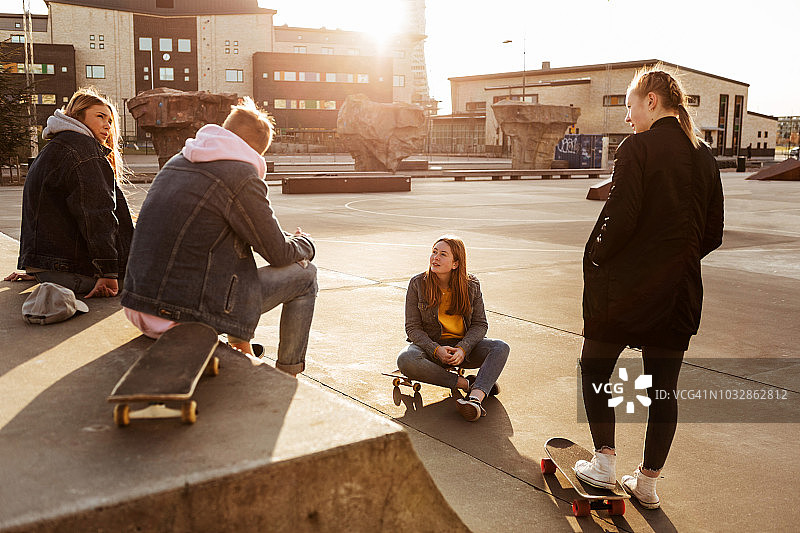 在阳光明媚的日子里，朋友们在城市的滑板公园闲逛时聊天图片素材