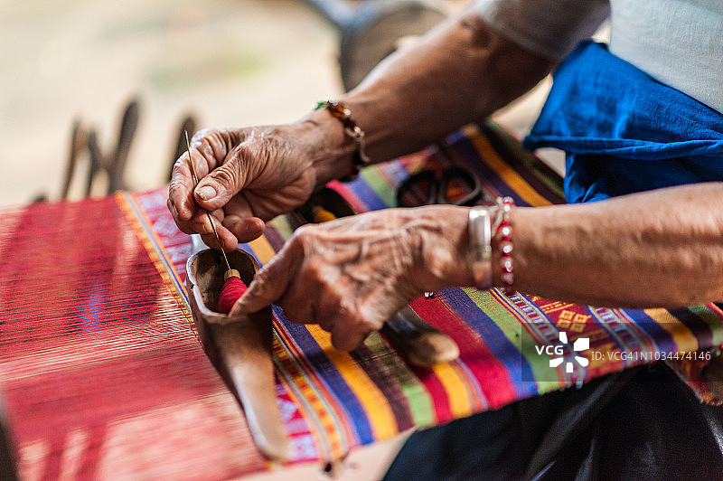越南麦洲河谷拉克村，当地妇女在织布机前辛勤工作，编织彩色织锦织物。图片素材