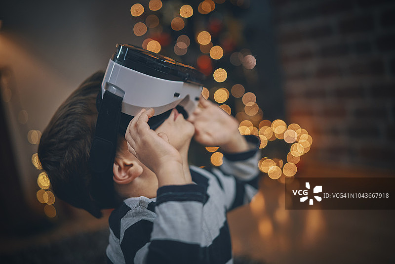 在舒适的圣诞氛围中，孩子们在客厅玩VR眼镜图片素材