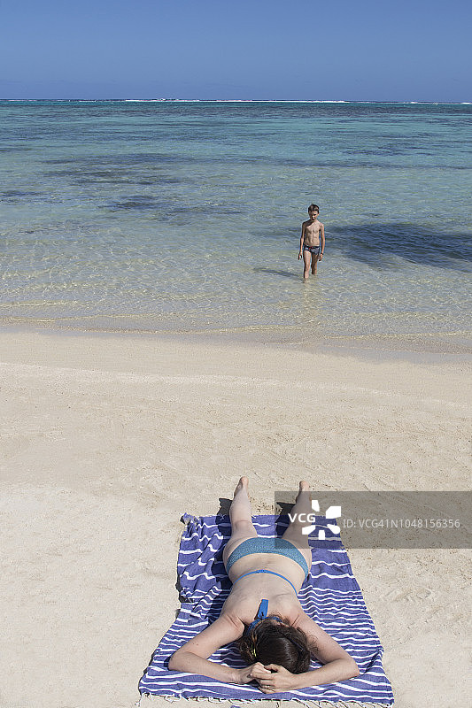 一个女人躺在沙滩上的毛巾上图片素材