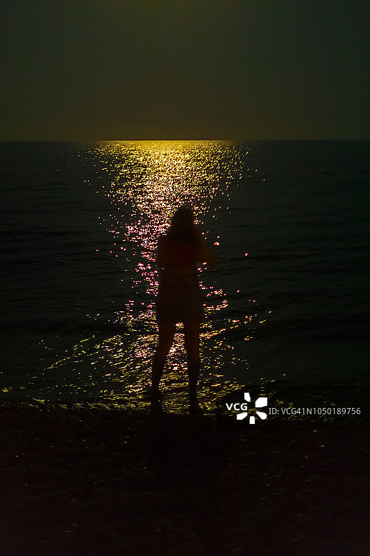 一个女人在月光下走向海边图片素材