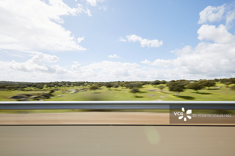 模糊的侧视汽车窗外的防撞护栏和风景在高速公路上图片素材