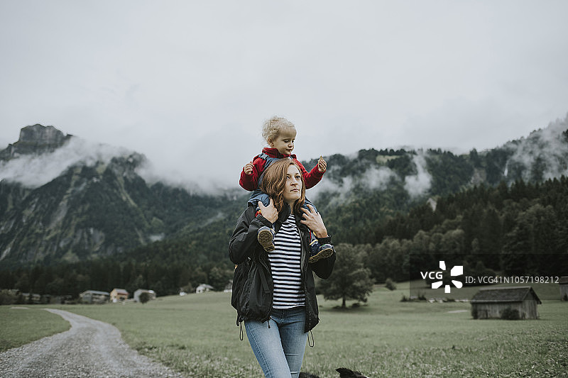 奥地利，Vorarlberg, Mellau，母亲背着蹒跚学步的孩子在山里旅行图片素材