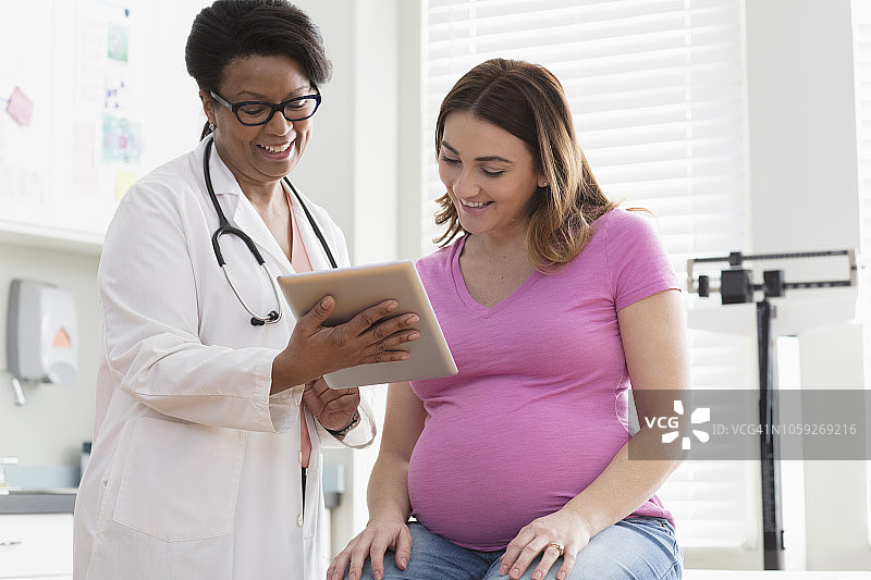 医生用平板电脑向孕妇展示超声波扫描图图片素材