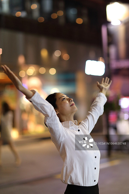 晚上在城市户外举起手臂的女商人图片素材