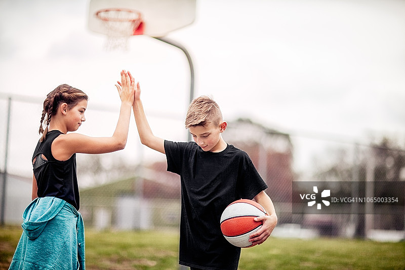十来岁的男孩和女孩在篮球比赛后互相击掌图片素材